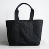 Front view of Hank the tote from Baxley. Shown in black with black webbing, with a front pocket visible.