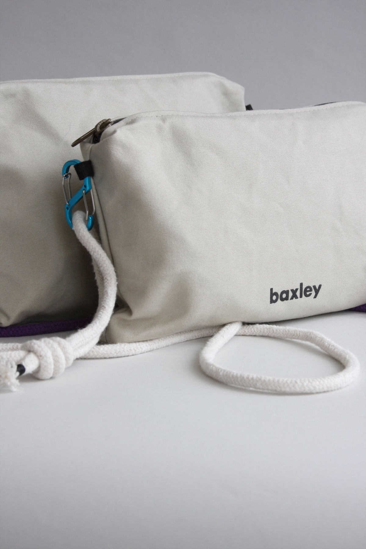 A close-up of Baxley's Effie crossbody bag in chalk white with a white rope strap and blue carabiner clasp.