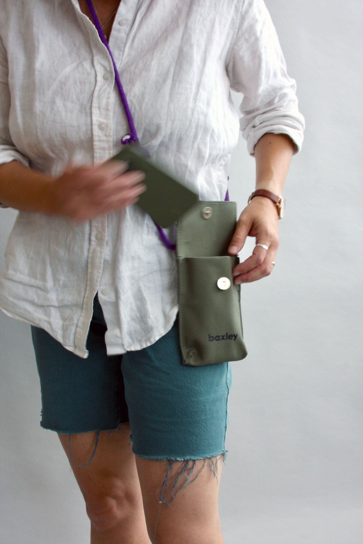 The female model is placing her phone into Pip the pocket. The bag is shown with flap open, with a magnet closure visible.