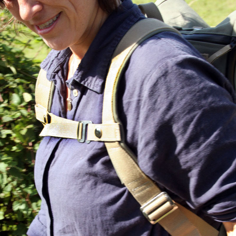 A beige version of the sternum strap is shown in use outside on a female model.