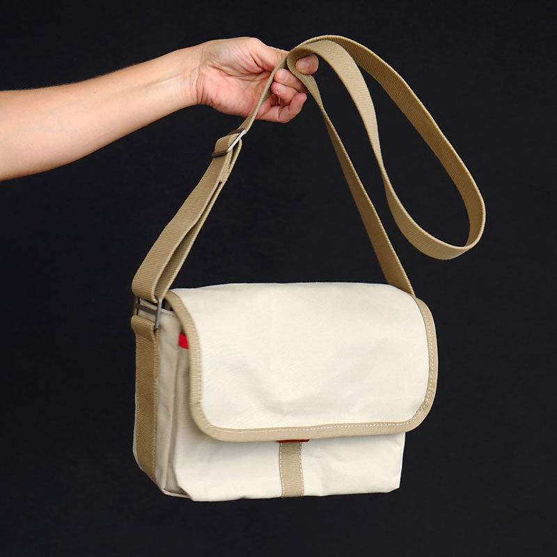 Gertie the crossbody satchel from Baxley is shown in chalk white, being held by an outstretched arm.
