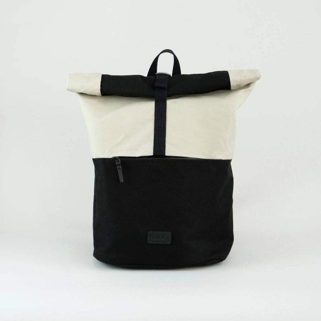 Front view of Max the backpack. A rolltop backpack made of waxed canvas in chalk white and black, with a front zipped pocket visible.