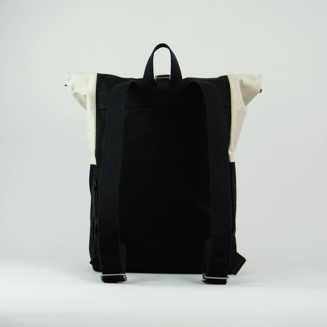 Rear view of Max the backpack. A rolltop backpack made of waxed canvas in chalk white and black.